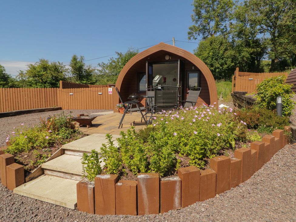 An outdoor glamping pod with seating and flower beds at Gortin Glen Glamping Pod 4 Omagh