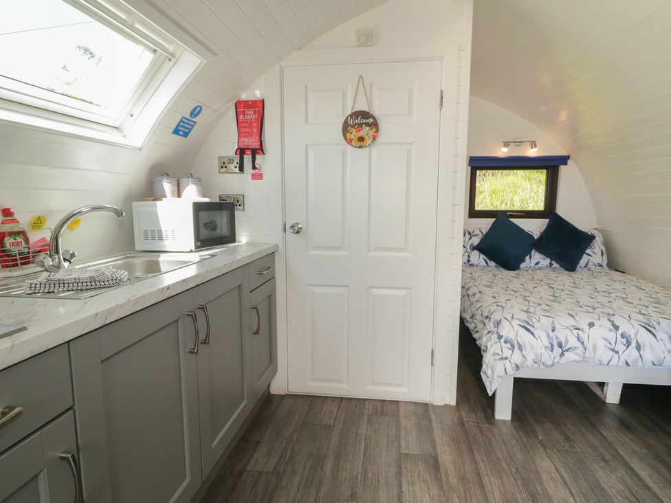 A kitchen area with a sink and microwave next to a sleeping area at Gortin Glen Glamping Pod 4 in Omagh