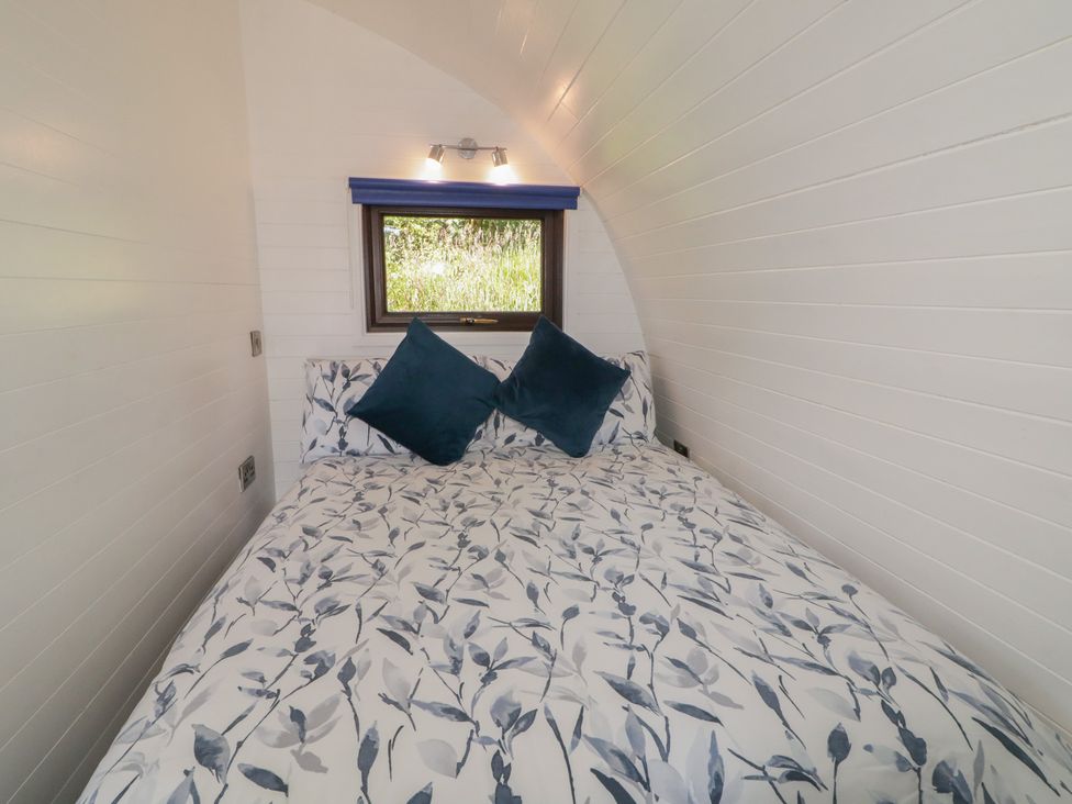 A bed with blue pillows and white bedding at Gortin Glen Glamping Pod 4 in Omagh
