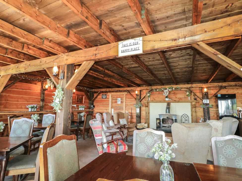 A common area with wooden beams, chairs and tables at Gortin Glen Glamping Pod 4 in Omagh
