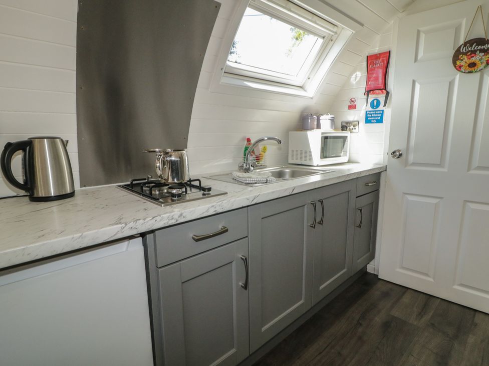 A kitchen with a stove, kettle, and microwave at Gortin Glen Glamping Pod 5 Omagh
