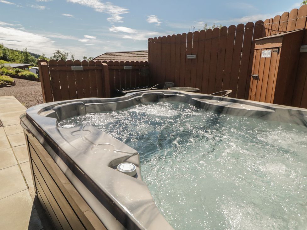 A hot tub with water and a fence at Gortin Glen Glamping Pod 5 Omagh