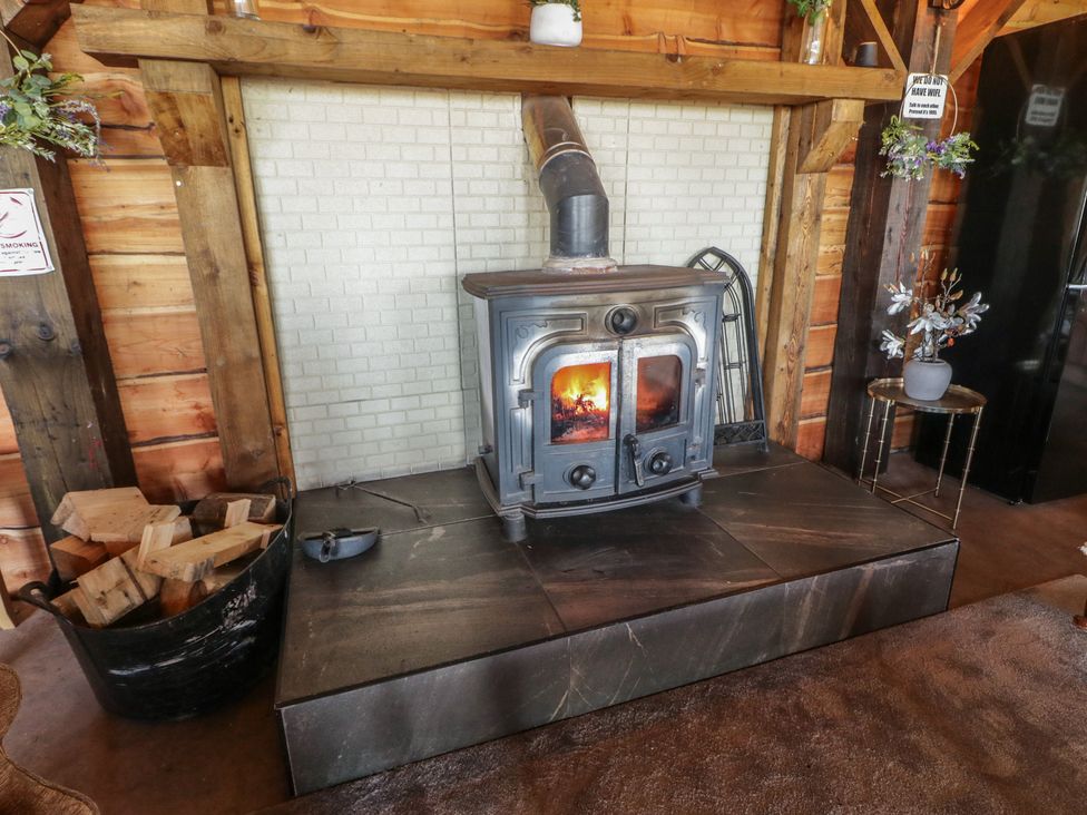 A living room with a wood stove and firewood at Gortin Glen Glamping Pod 5, Omagh