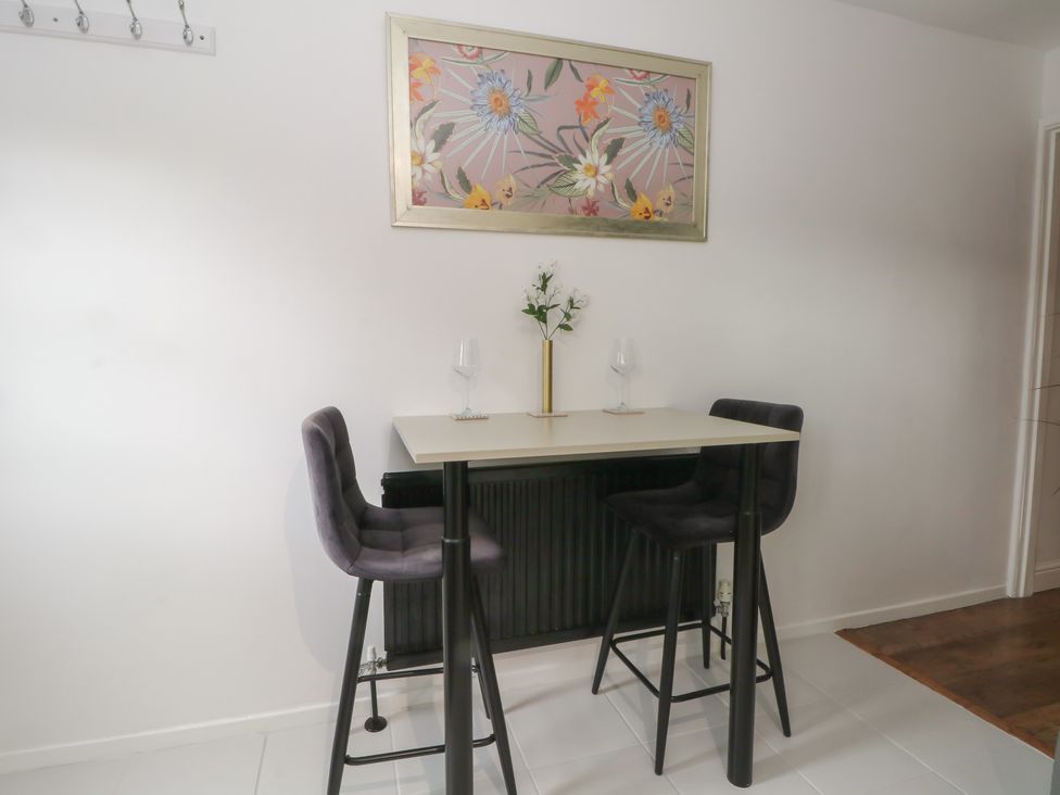 A dining area with a table and two bar stools at Coastal Cottage in Lytham St. Annes
