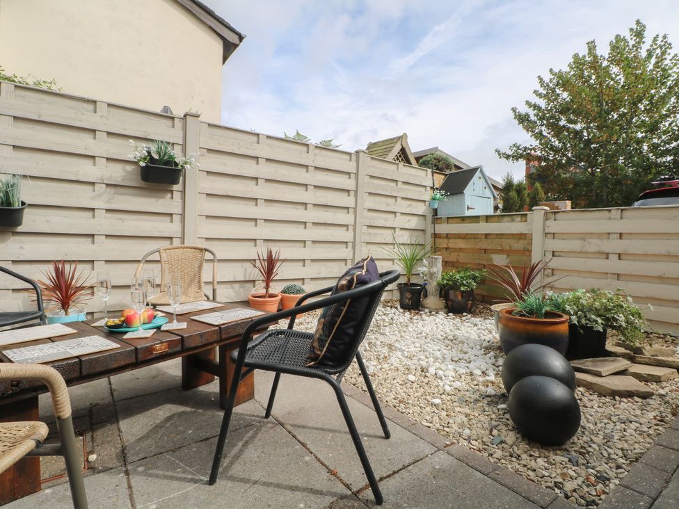A garden with a table and chairs surrounded by plants at Coastal Cottage in Lytham St. Annes