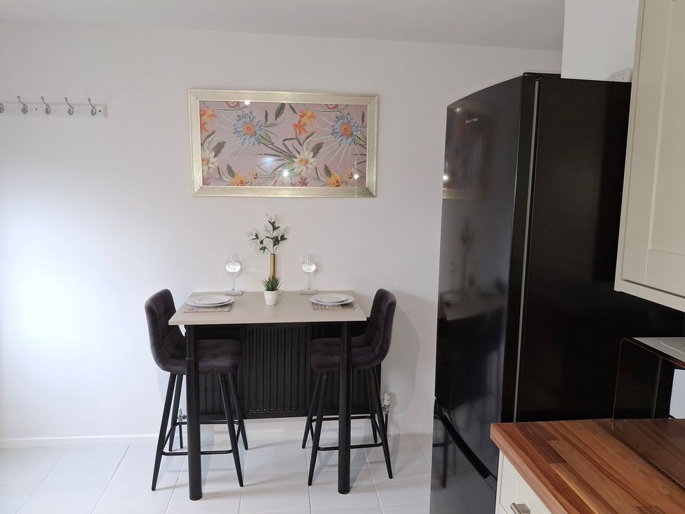 A kitchen with a table and stools at Coastal Cottage in Lytham St. Annes