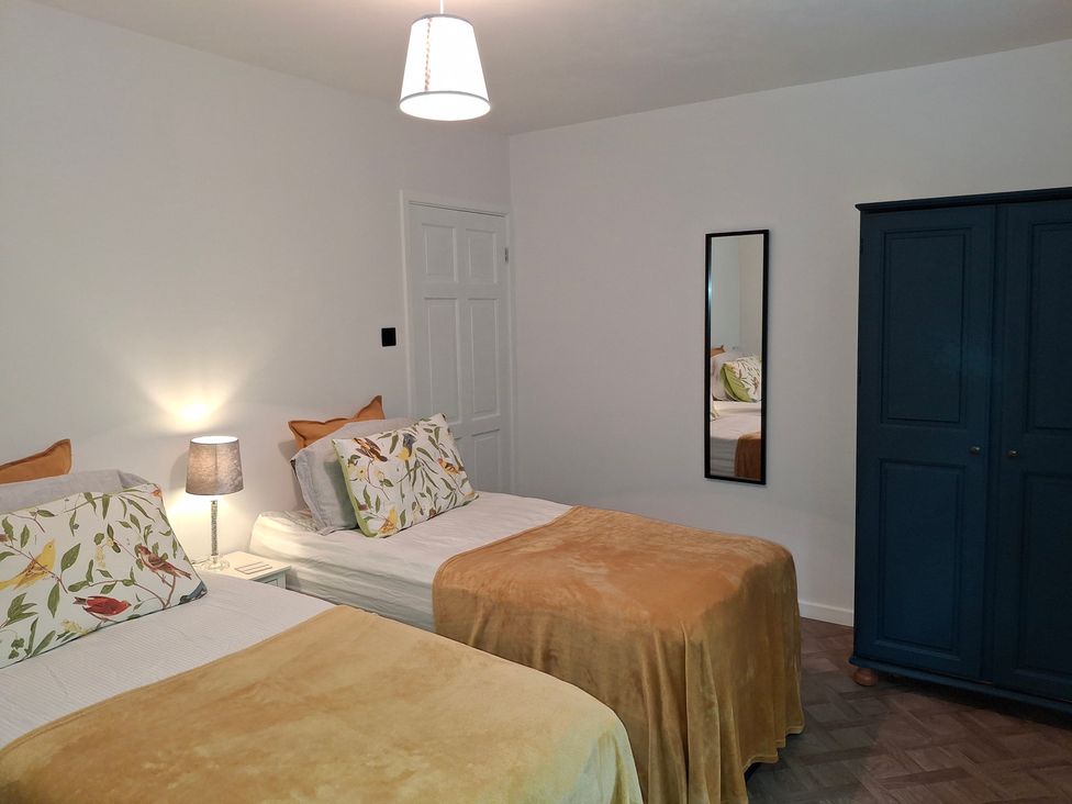A bedroom with two beds and a wardrobe at Coastal Cottage in Lytham St. Annes