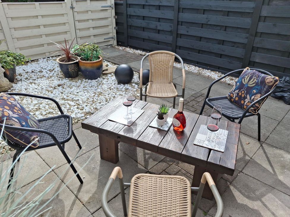 An outdoor patio with a wooden table and chairs at Coastal Cottage in Lytham St. Annes