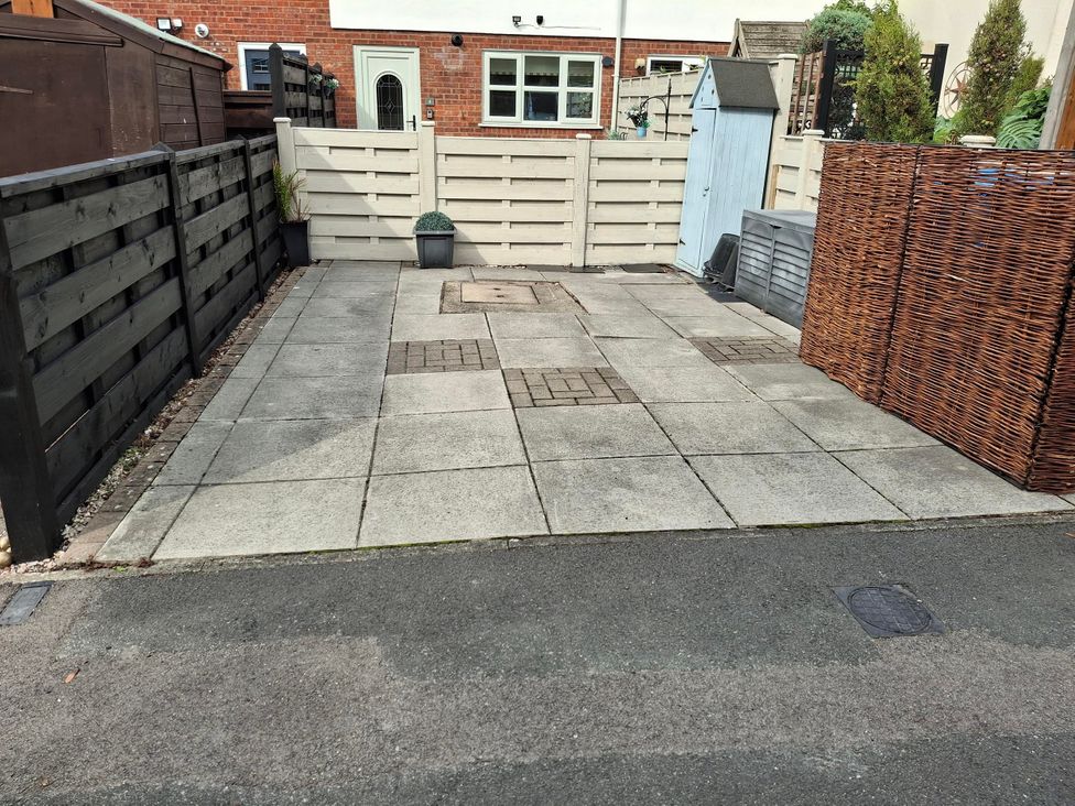An outdoor area with a patio, fence, storage shed, and planters at Coastal Cottage in Lytham St. Annes