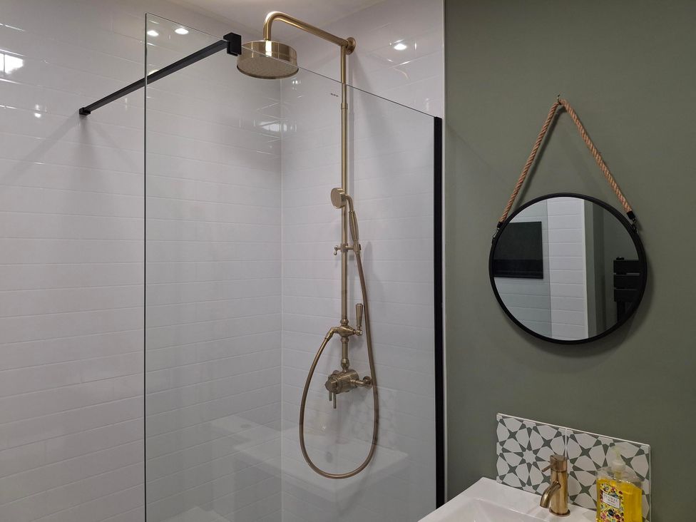 A bathroom with a shower, mirror, and sink at Coastal Cottage in Lytham St. Annes