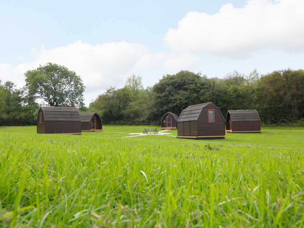 An outdoor area with several cabins and a picnic table at Skylark Pod in Swannington near Coalville