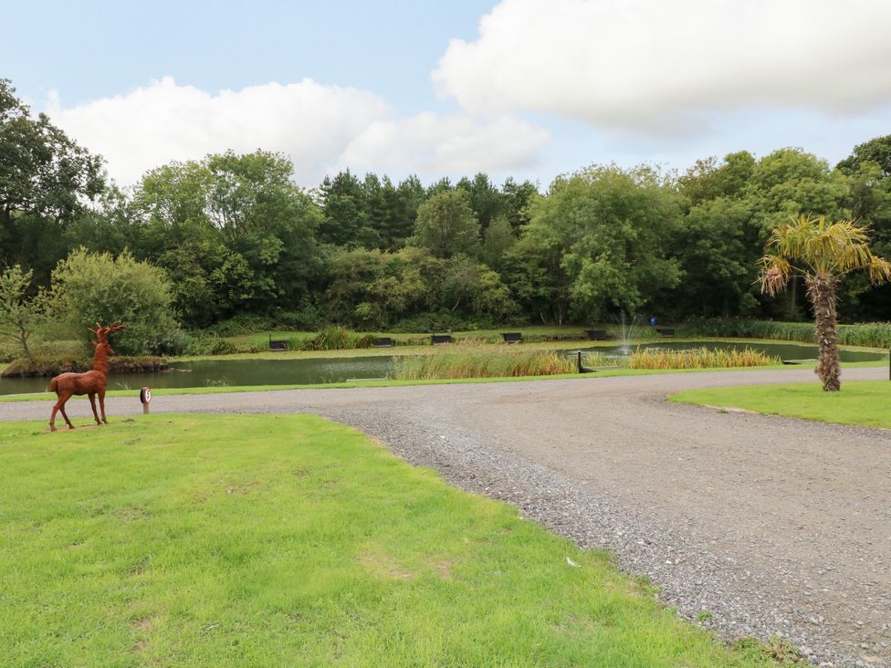 A pond with a deer sculpture and palm tree at Skylark Pod Swannington near Coalville