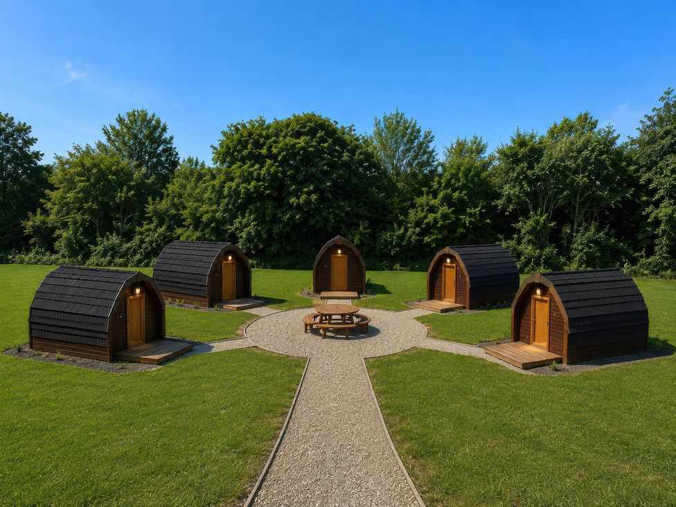 A group of cabins arranged around a table in a garden at Yellow hammer Pod in Coalville
