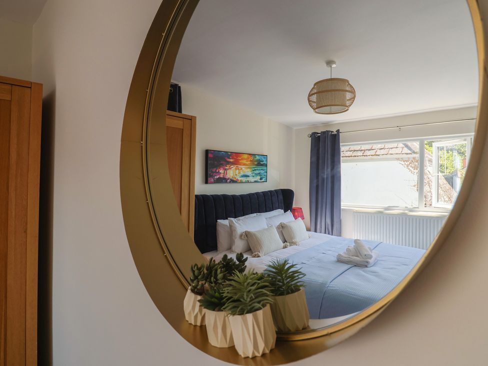 A bedroom with a bed and mirror at 2 Mill Green Court in Lyme Regis
