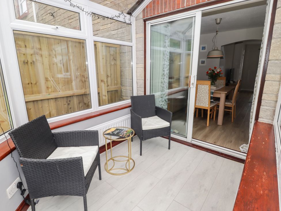 A conservatory with chairs and a table at 7 Cwrt Y Cadno in Llantwit Major