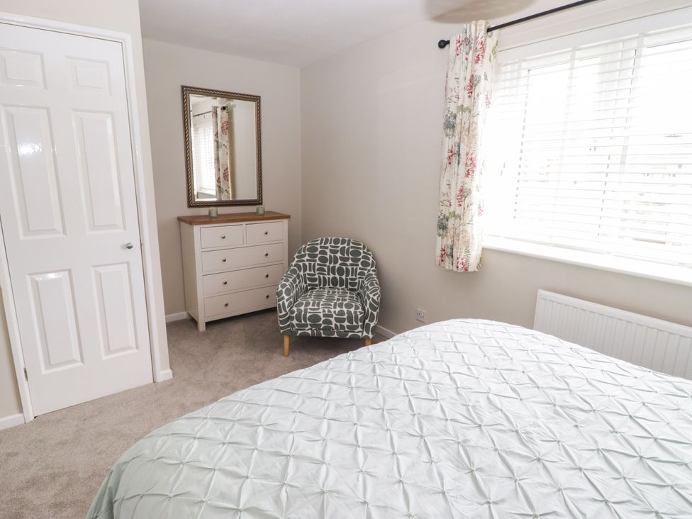 A bedroom with a bed, chair, dresser and mirror at 7 Cwrt Y Cadno Llantwit Major