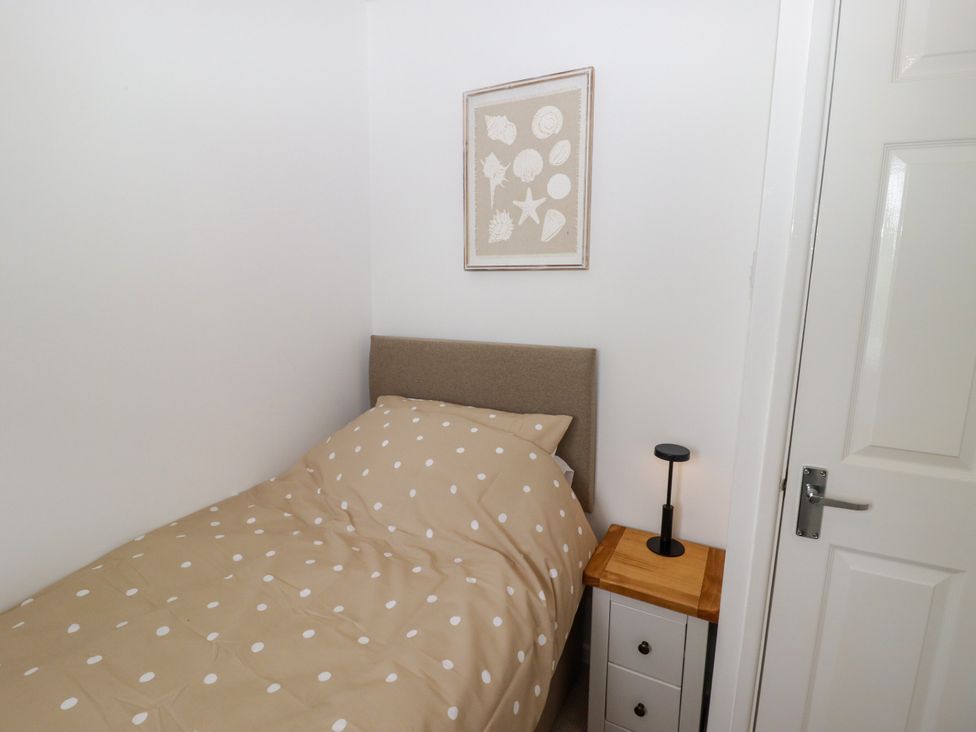A bedroom with a single bed, nightstand, and wall art at 7 Cwrt Y Cadno in Llantwit Major