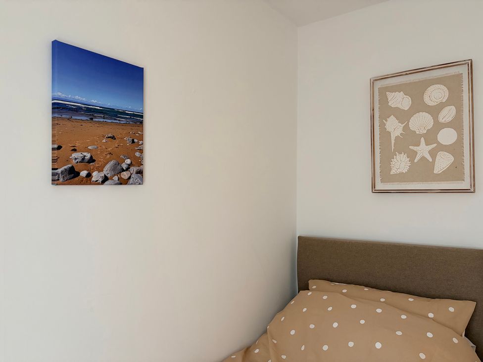 A bedroom with a beach photo and shell artwork at 7 Cwrt Y Cadno in Llantwit Major