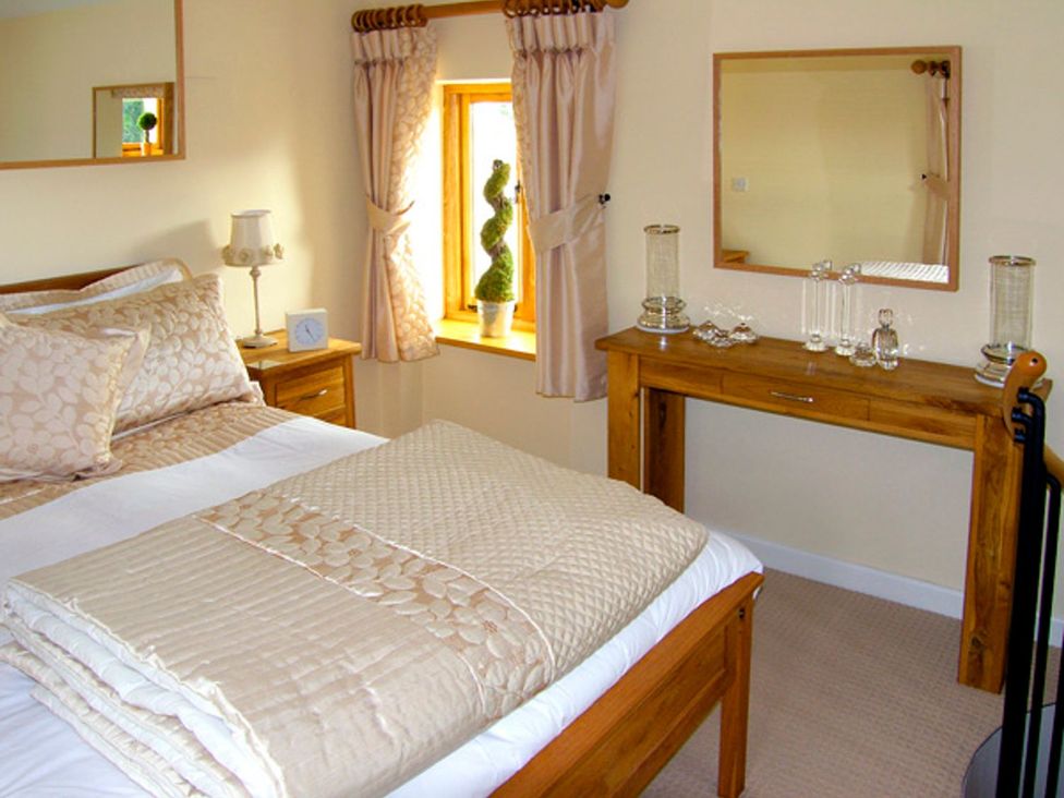 A bedroom with a bed and a wooden table at Howle Hideaway in Ross-on-Wye