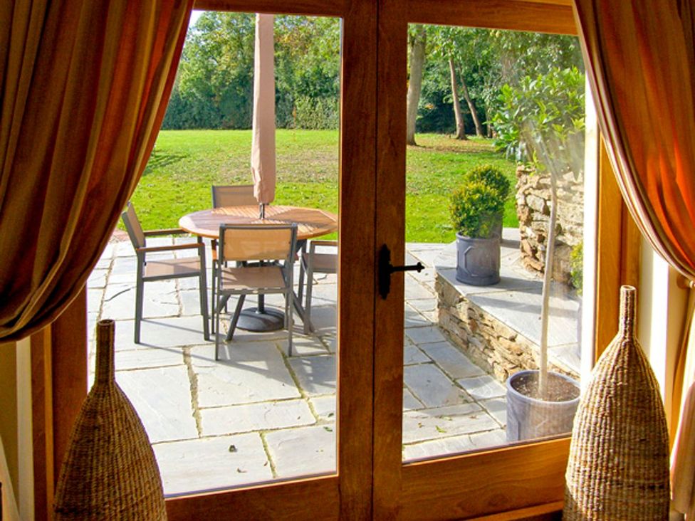 A patio area with a table and chairs visible through a door at Howle Hideaway in Ross-on-Wye