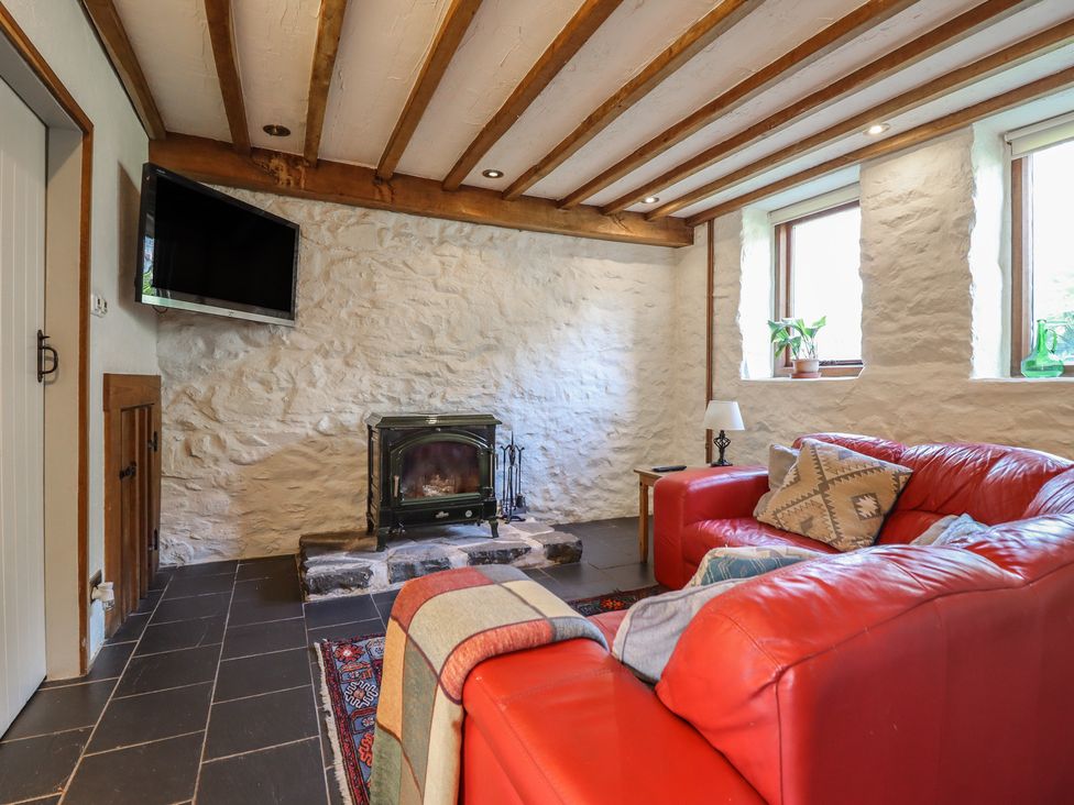 A living room with a television, fireplace, and red couch at Pandy Farmhouse 