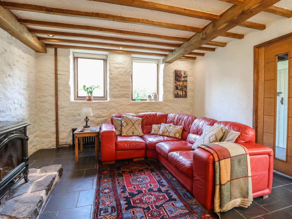 A living room with a red sofa and fireplace at Pandy Farmhouse