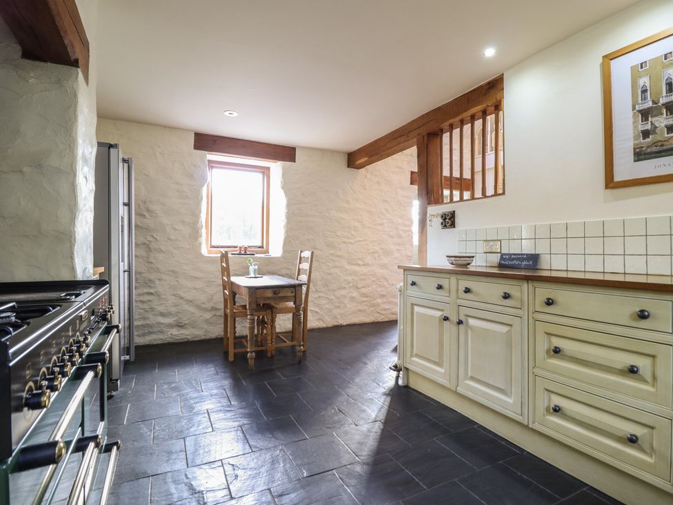 A kitchen with a stove, refrigerator, and table at Pandy Farmhouse