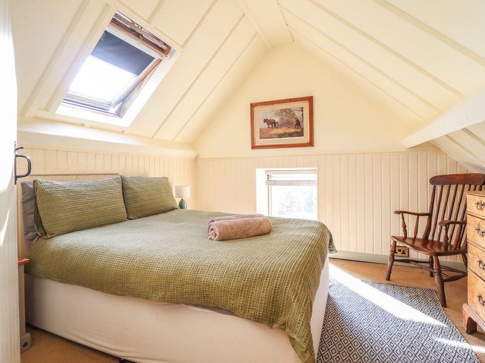 A bedroom with a bed and a rocking chair at Pandy Farmhouse