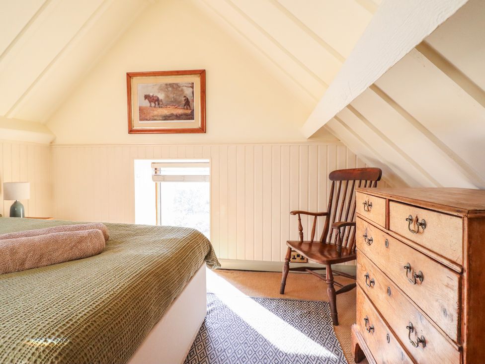 A bedroom with a bed, chair, and dresser at Pandy Farmhouse
