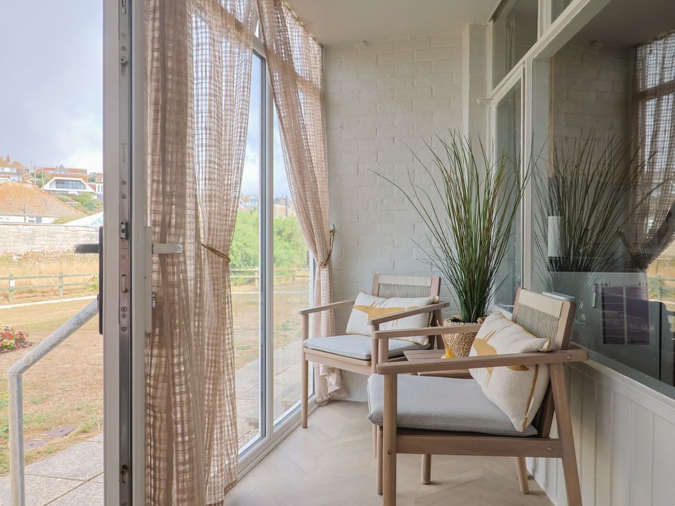 A conservatory with chairs and a potted plant at 4 Kingfisher Court in West Bay