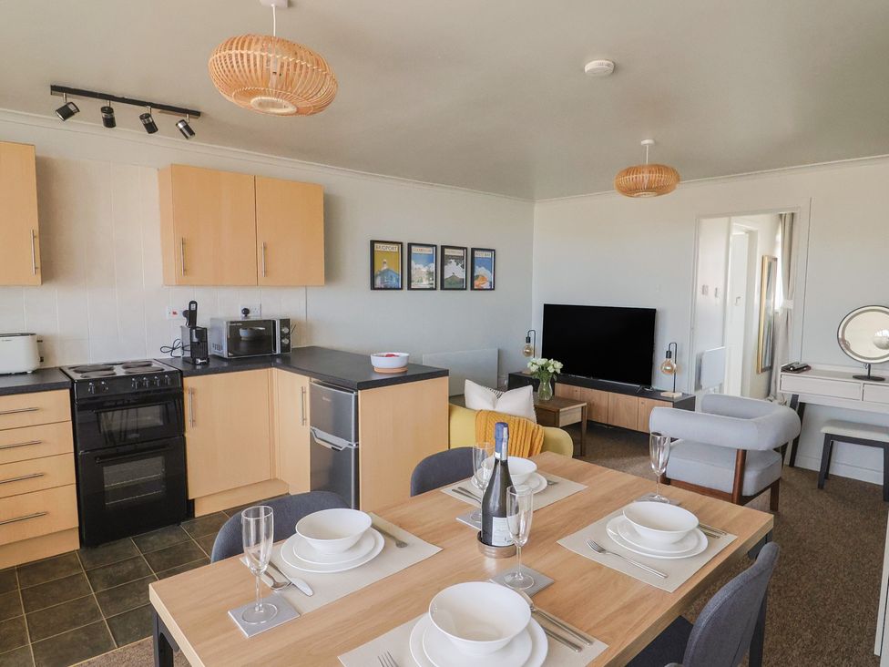 A kitchen and living room with appliances and dining setup at 4 Kingfisher Court West Bay