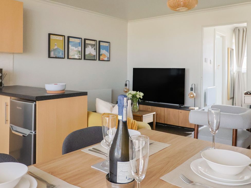 A living room with a dining table and a television at 4 Kingfisher Court, West Bay