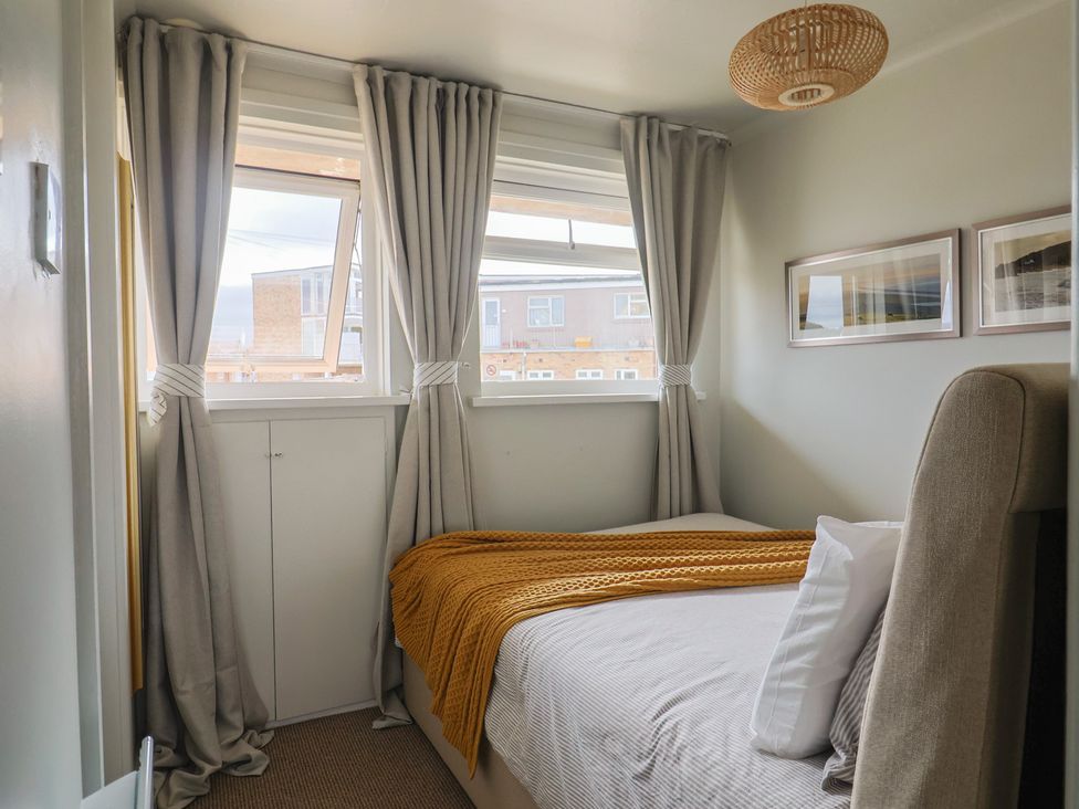 A bedroom with a bed and curtains at 4 Kingfisher Court West Bay