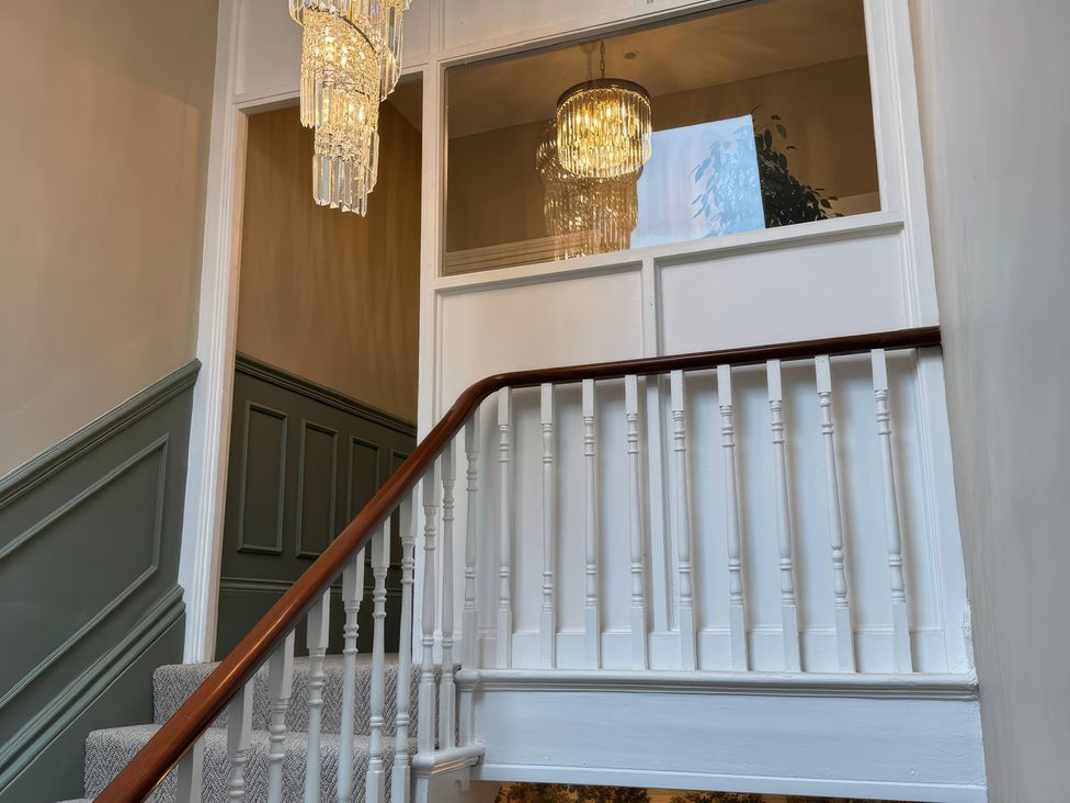A staircase with a chandelier and a railing at The Buxton Suite in Buxton