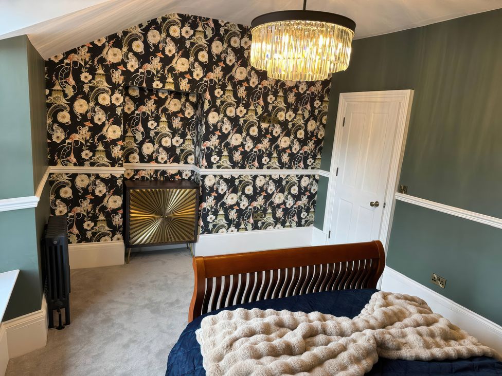 A bedroom with a bed and a decorative chandelier at The Buxton Suite in Buxton