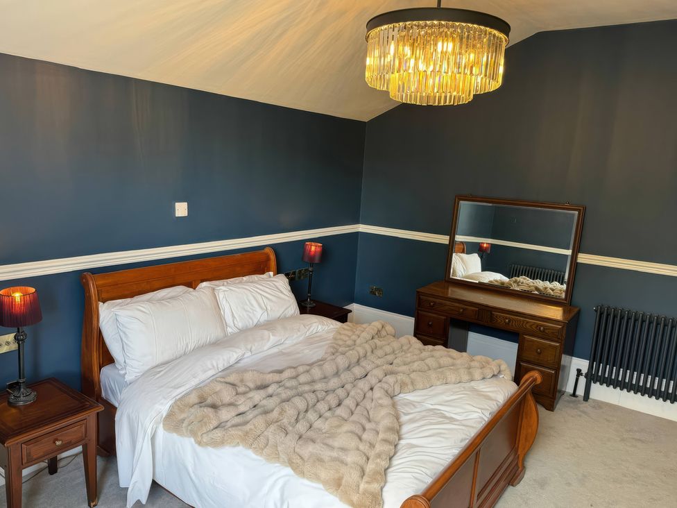 A bedroom with a bed and mirror at The Buxton Suite in Buxton