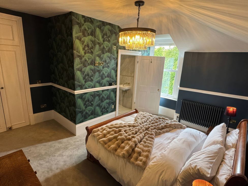 A bedroom with a bed and a bathroom door at The Buxton Suite in Buxton