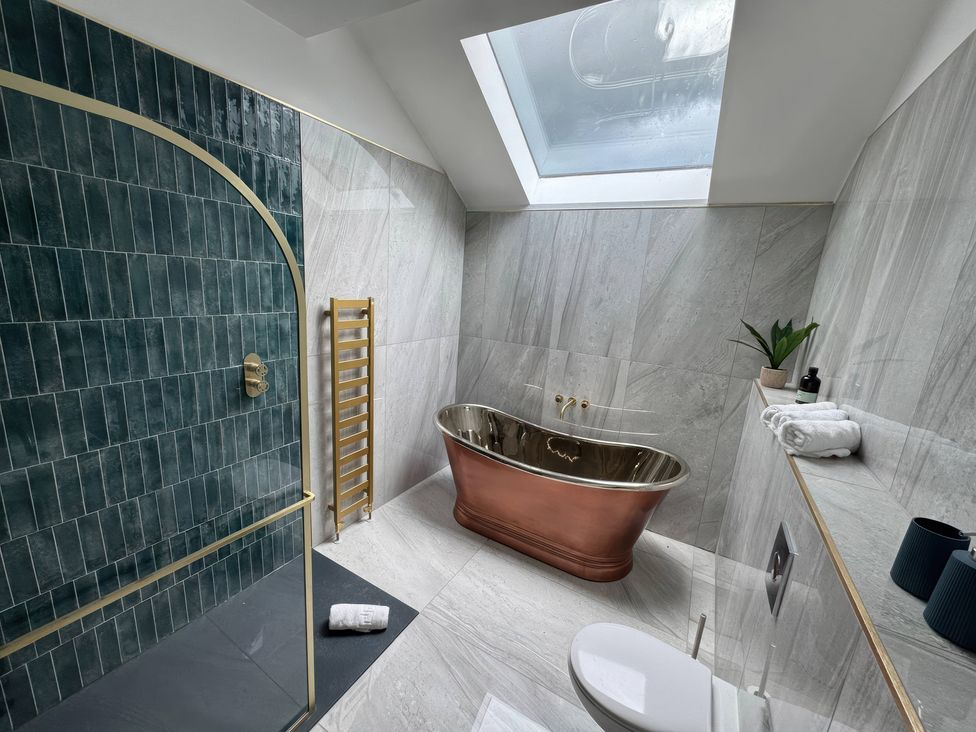 A bathroom with a bathtub, shower, toilet and accessories at The Buxton Suite in Buxton