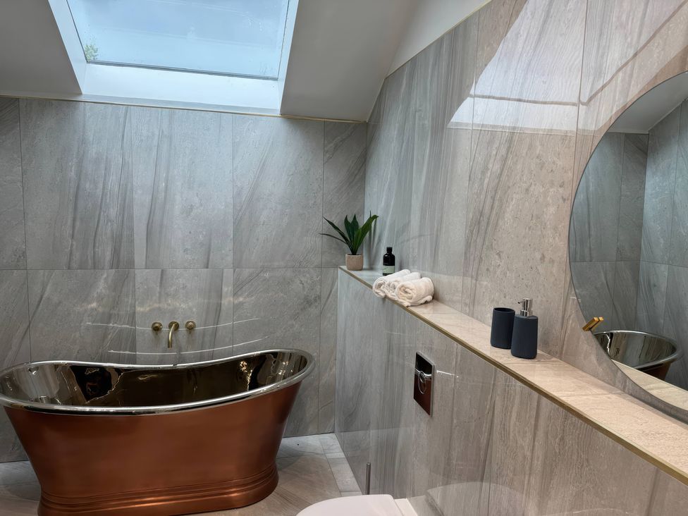 A bathroom with a bathtub and towels at The Buxton Suite in Buxton