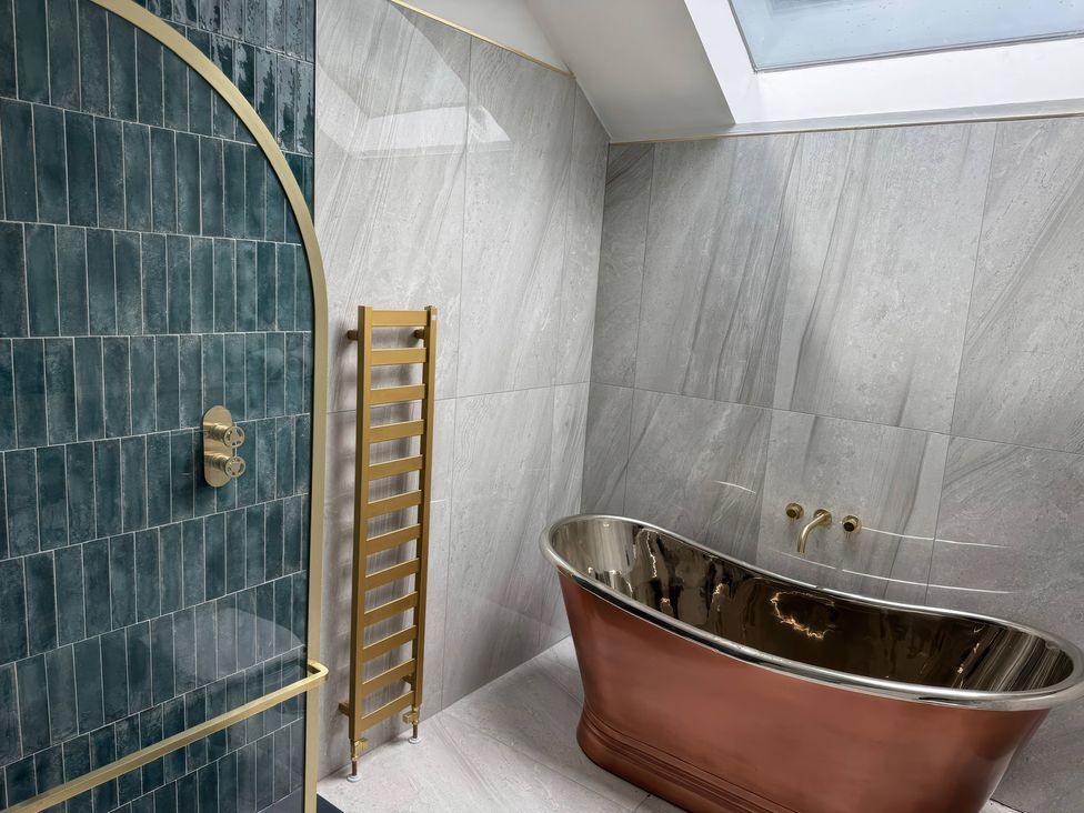 A bathroom with a copper bathtub and a walk-in shower at The Buxton Suite in Buxton