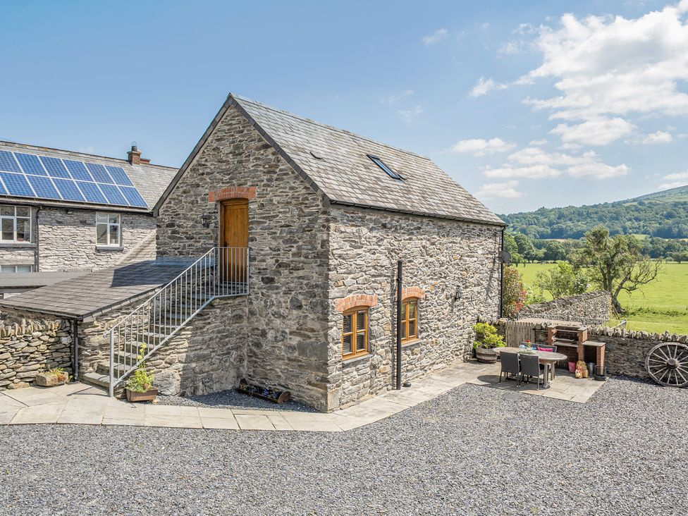 An outdoor area with a stone building and furniture at The Granary in Corwen