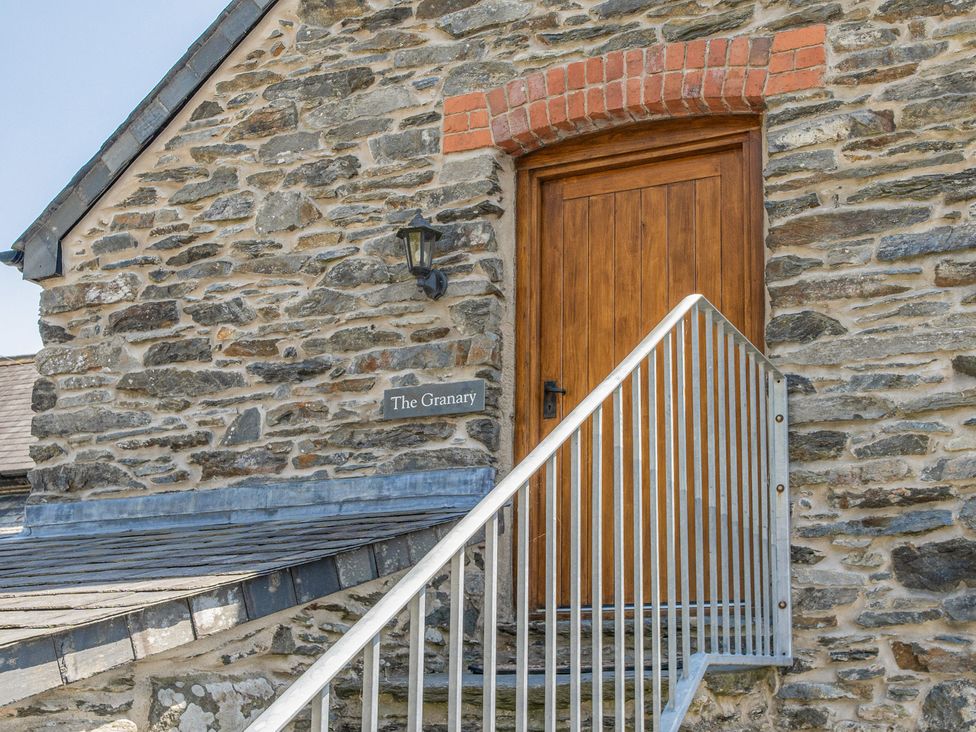 An entrance with a wooden door and stone wall at The Granary in Corwen