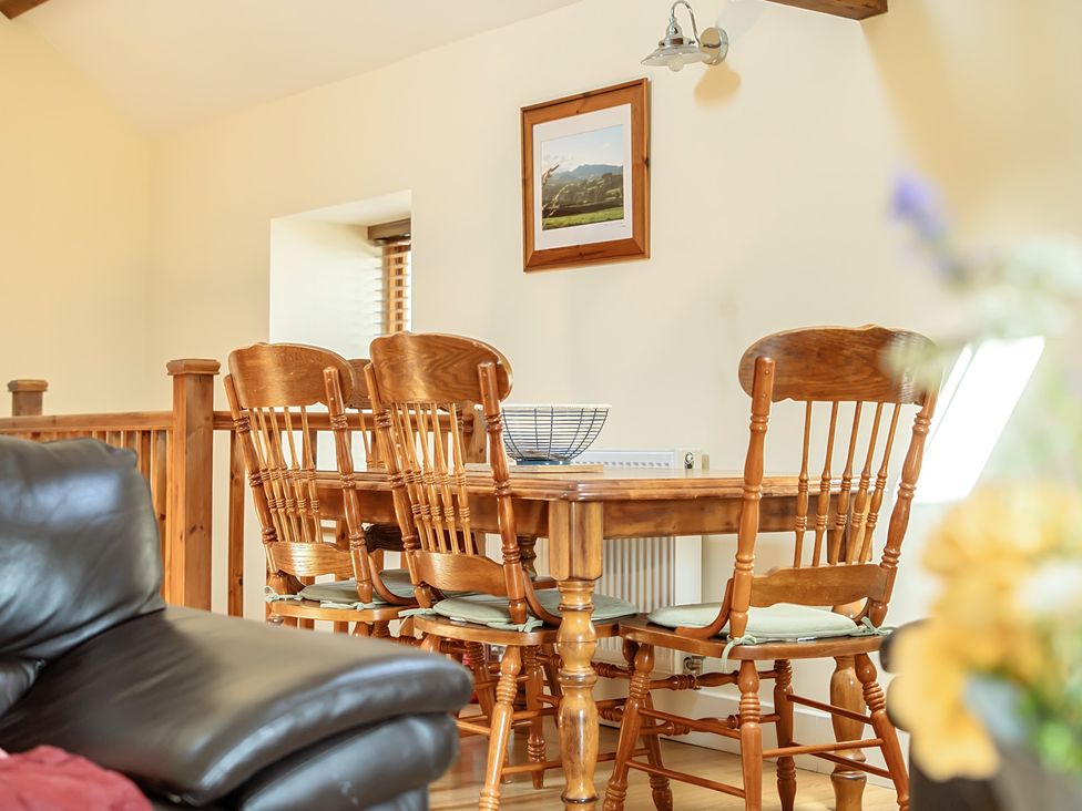 A dining room with a wooden table and chairs at The Granary in Corwen