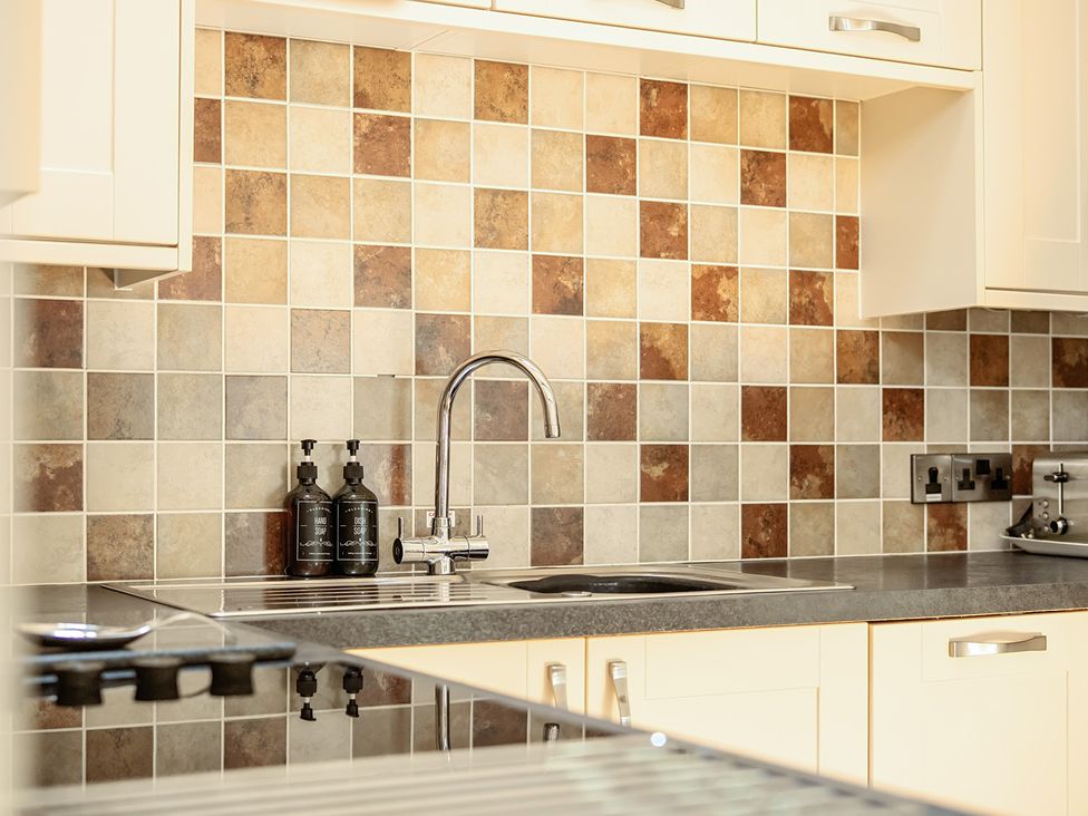 A kitchen with a sink and tiled backsplash at The Granary in Corwen