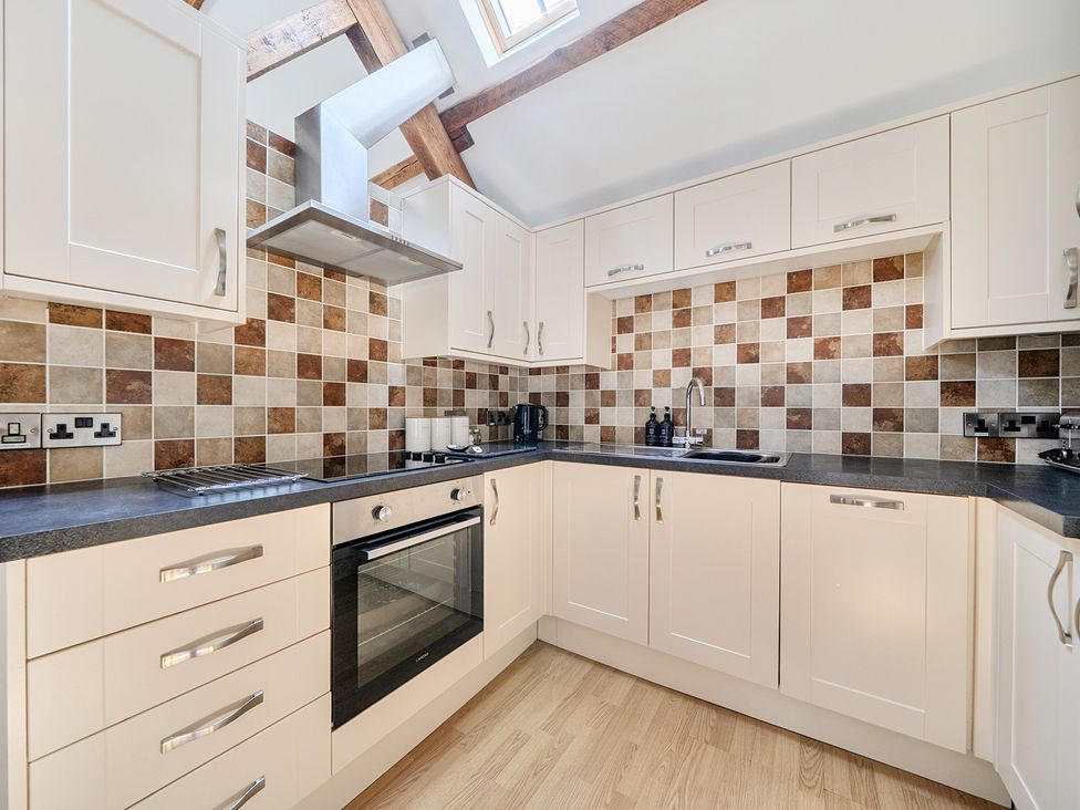 A kitchen with cabinets, oven, and sink at The Granary in Corwen