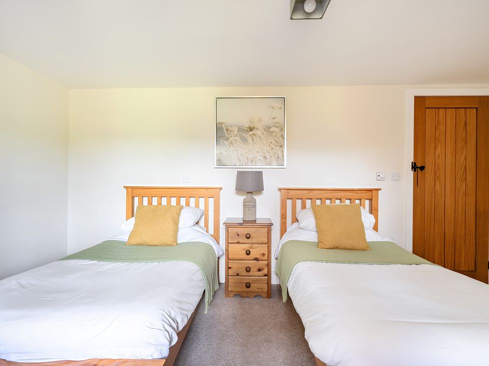 A bedroom with two beds and a nightstand at The Granary in Corwen