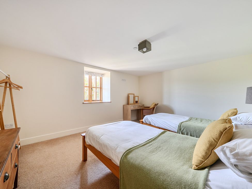 A bedroom with two beds and a desk at The Granary in Corwen
