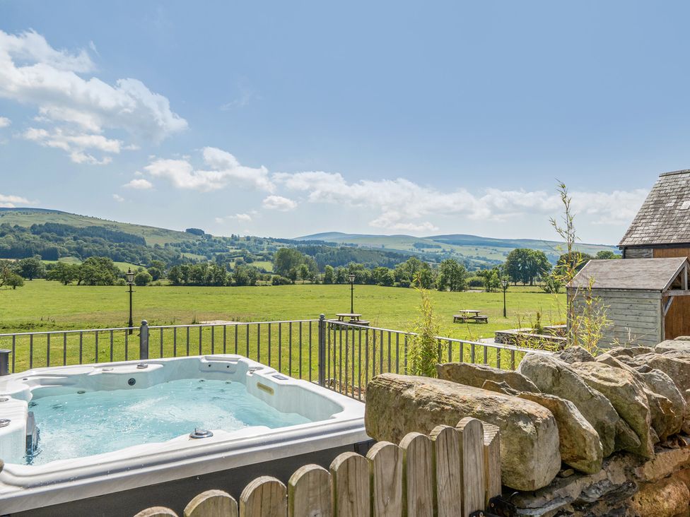An outdoor area with a hot tub and view of fields and mountains at The Granary Corwen
