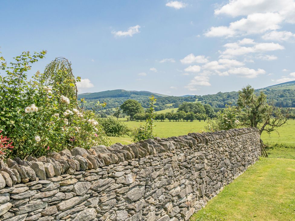 A view with a stone wall and green fields at The Granary Corwen