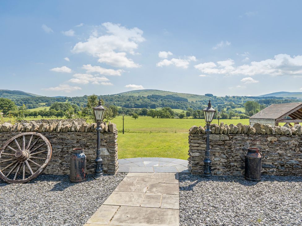 A view from a stone wall with a lamppost and wheel at The Granary in Corwen